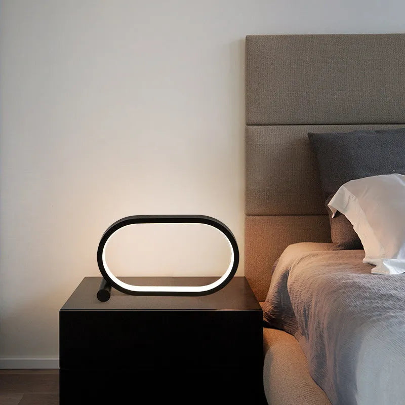 USB plug-in oval acrylic touch control night light with metal base, black finish, on a bedside table