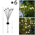 Solar-powered LED firefly garden stake light with stainless steel ground plug illuminated at dusk.