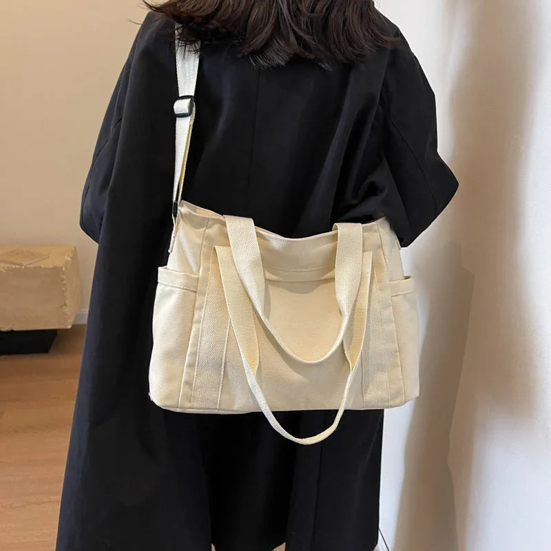 Large solid colour polyester canvas shoulder bag for women showing external pocket and strap.