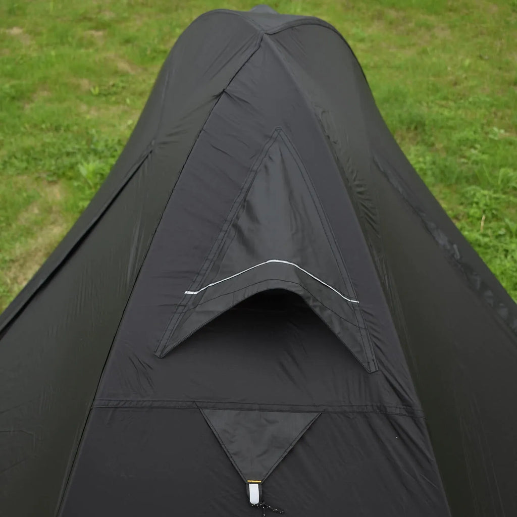 Red single person backpacking tent with aluminium poles pitched in a forest, showing double-layer design and vestibule.