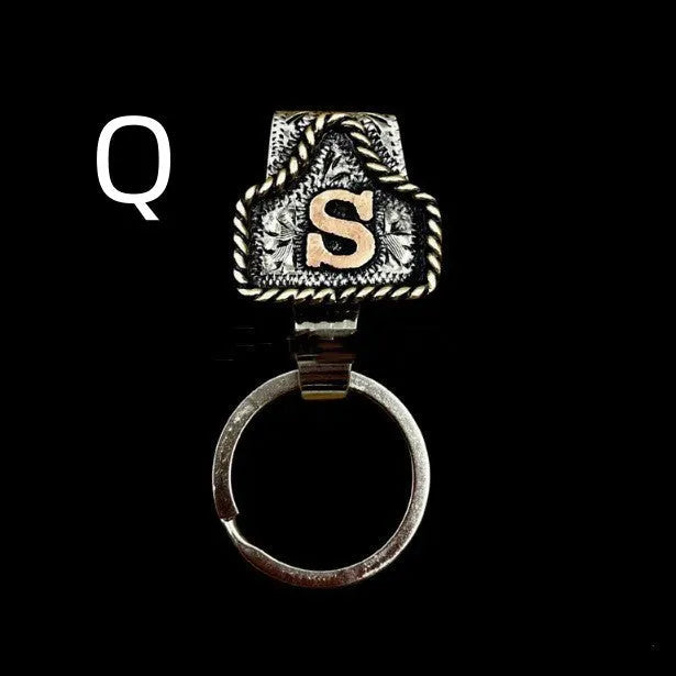 Handmade metal cow tag belt keychain showing one of 26 colour options, each marked with a different alphabet letter.