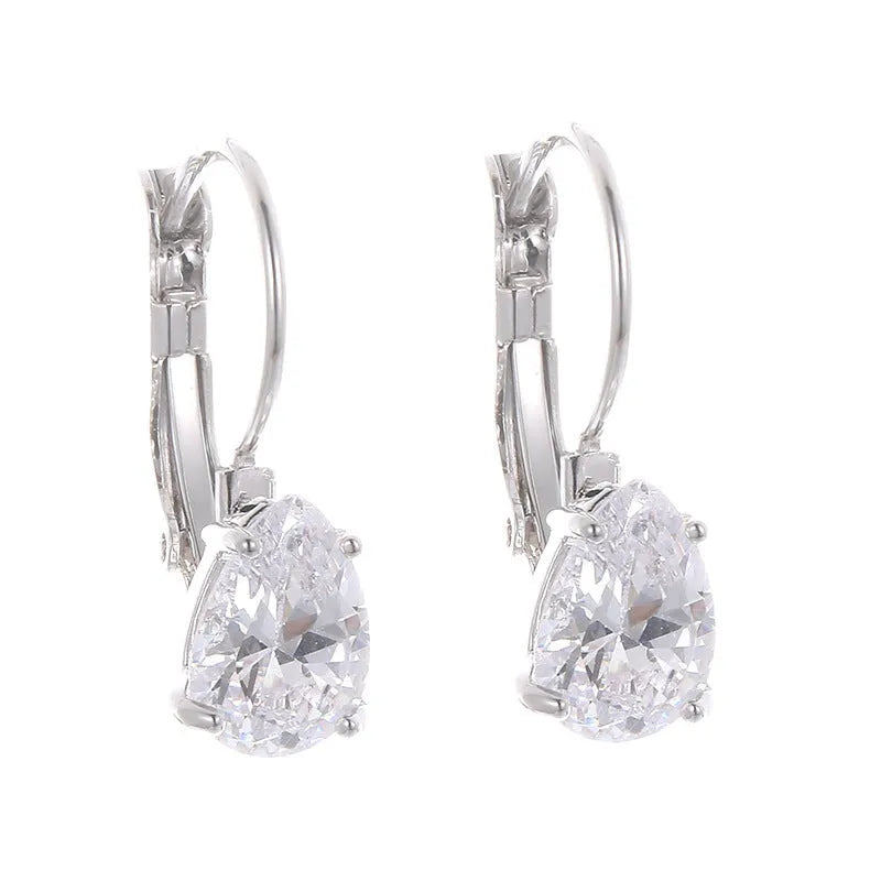 A pair of simple drop-shaped copper earrings with a platinum gem setting, shown in gold colour.
