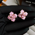 A pair of gold-plated purple flower stud earrings with a mottled oil-spot glaze on a copper base.