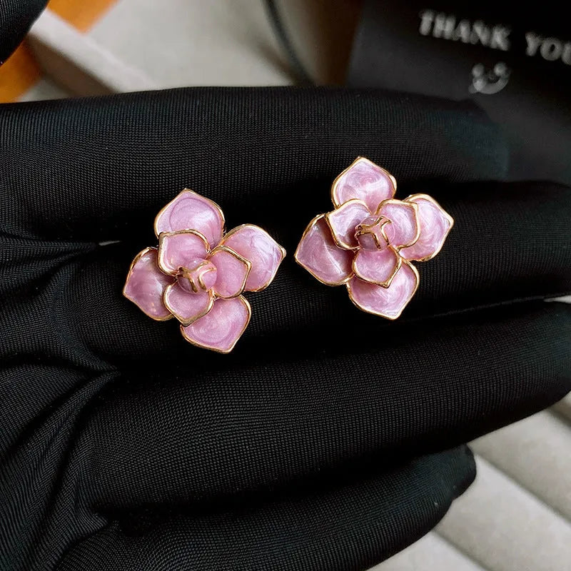 A pair of gold-plated purple flower stud earrings with a mottled oil-spot glaze on a copper base.