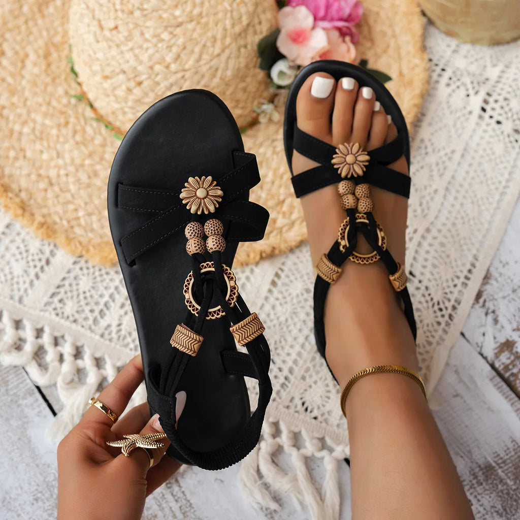 Black women's flat open-toe beach sandals with beaded weave upper, rhinestone decoration, and elastic band.