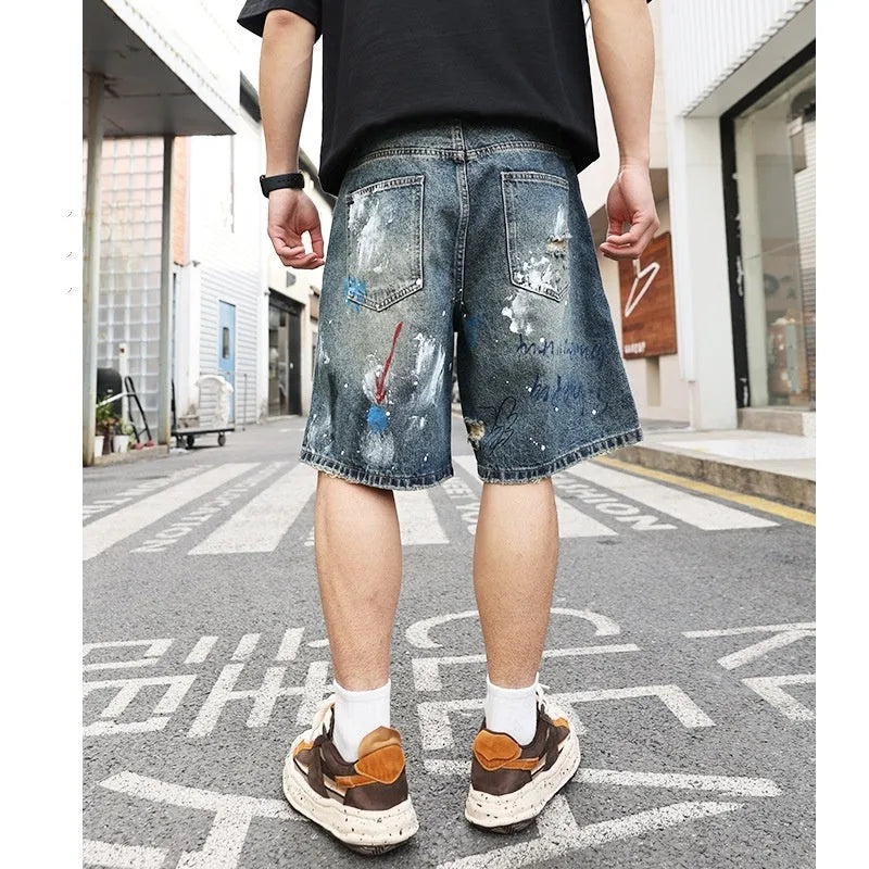 Blue denim shorts for men with ripped knees and graffiti design, featuring a straight leg and zipper fly.
