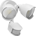 White outdoor LED security flood light with motion sensor mounted on a wall beside a garage door.