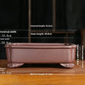 Antique rectangular purple sand bonsai pot with manger design on a floor.