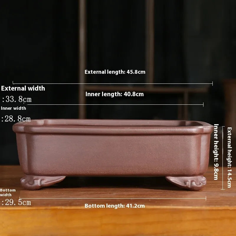 Antique rectangular purple sand bonsai pot with manger design on a floor.