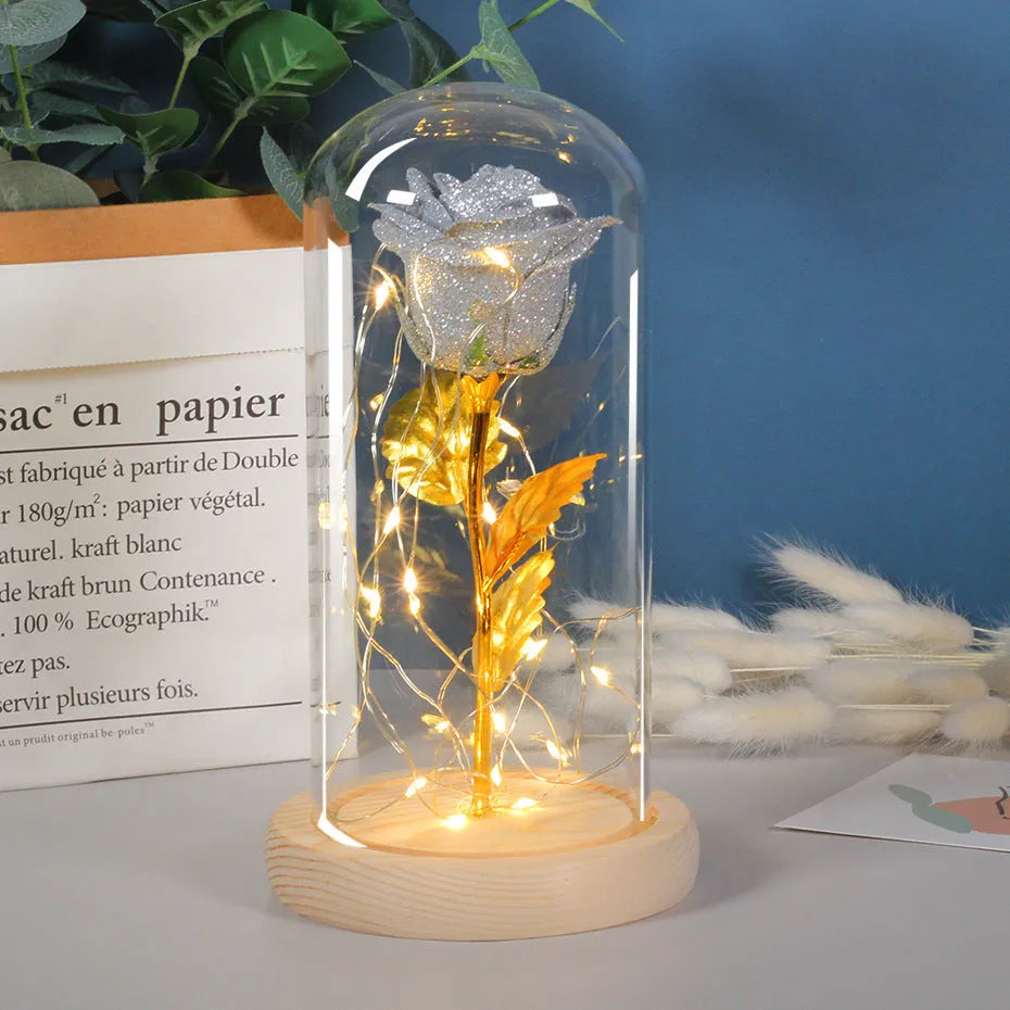 Red eternal rose in glass cover with warm white LED strip lit on dark surface