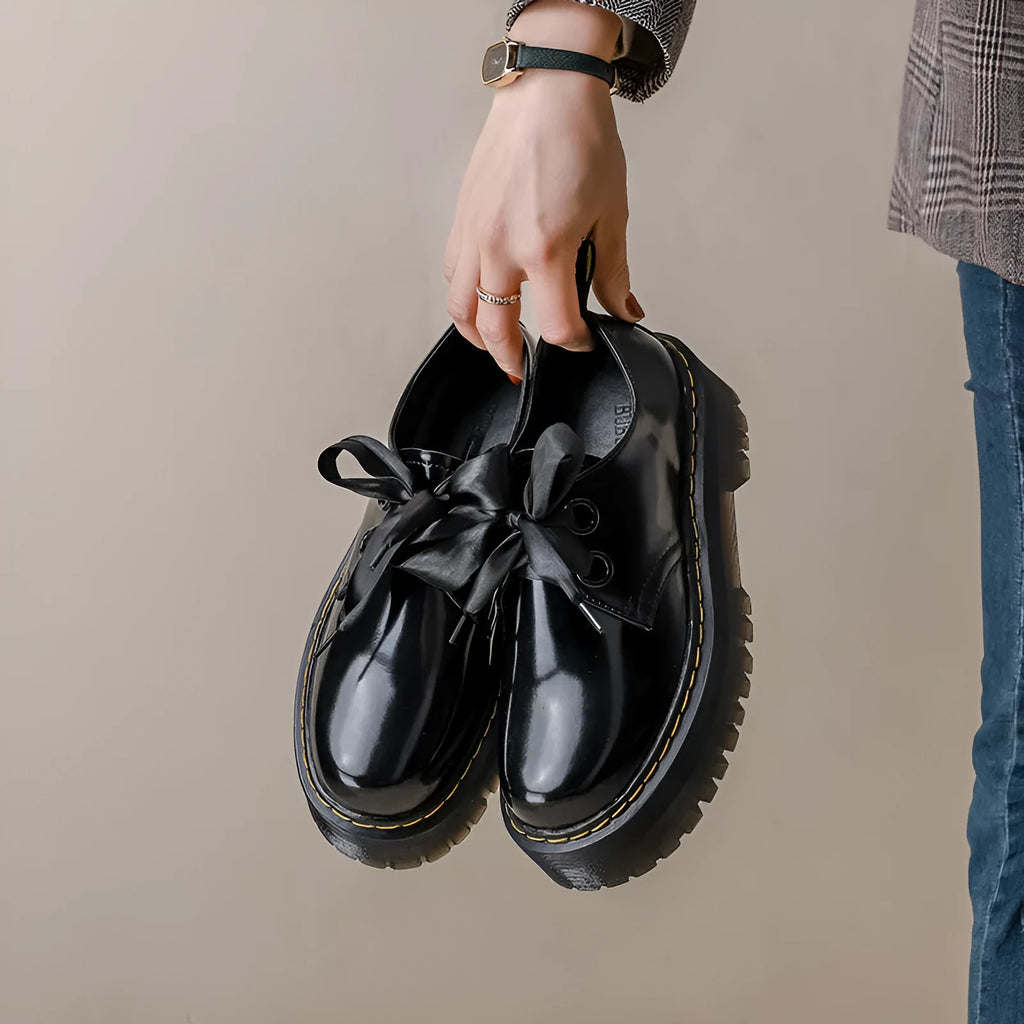 Black and white women's thick-soled leather shoes with ribbon cross straps and laces.