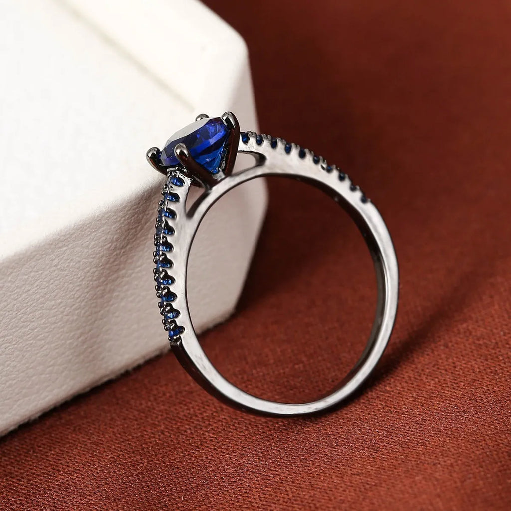 Close-up of a hexagonal geometric copper ring with a central zircon stone in a gun black and purple electroplated finish.