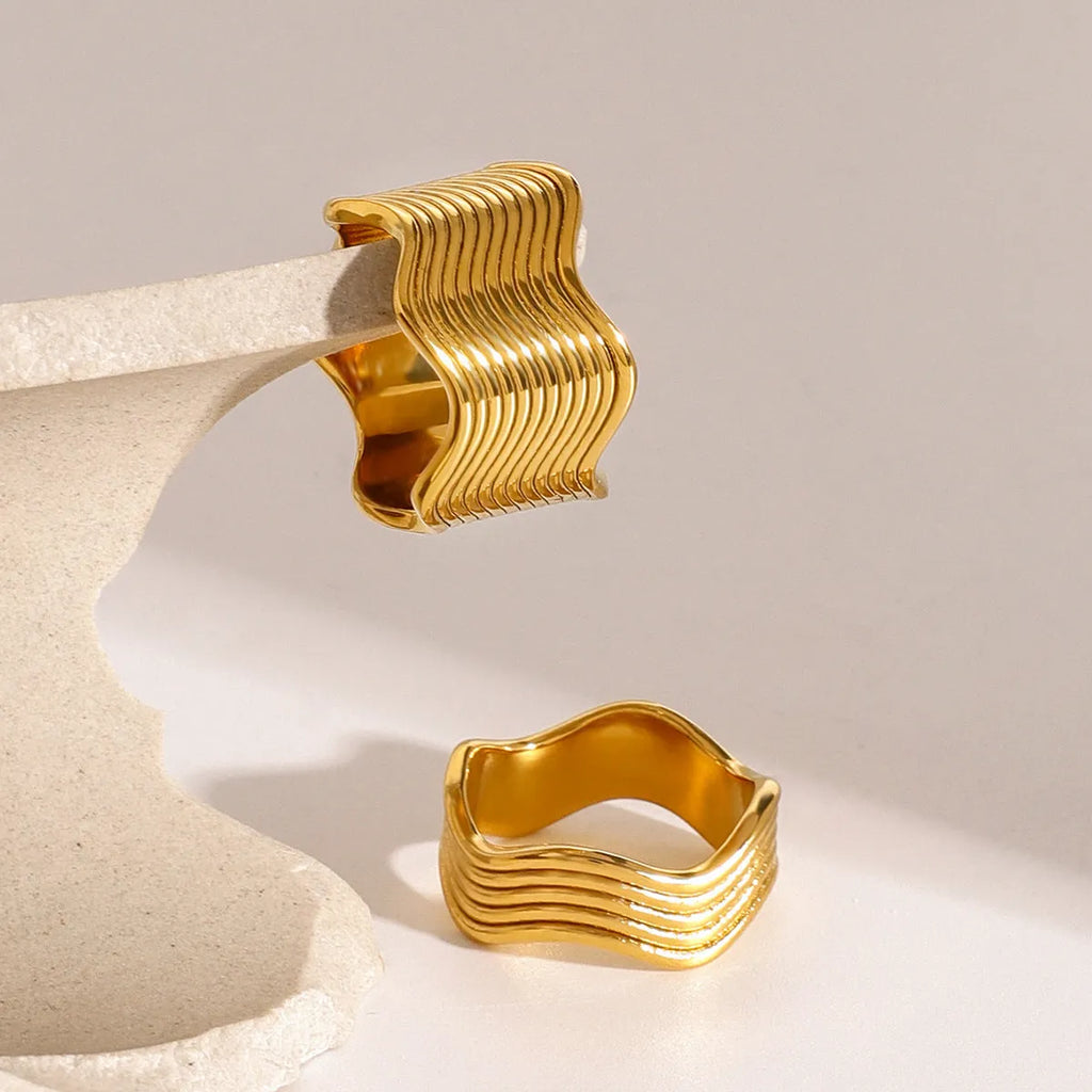 Stainless steel wide band ring with a geometric wave pattern, shown in an electroplated colour option.