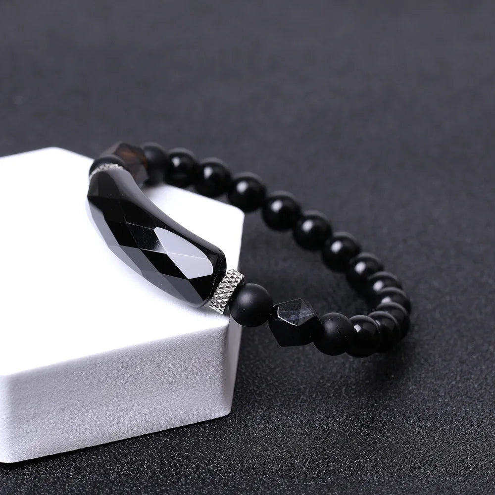 Close-up of a handmade diamond-cut black agate bracelet with geometric, fan-shaped design elements.