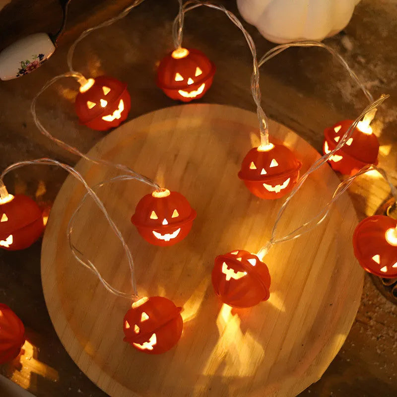 Halloween pumpkin string lights with warm white LEDs and iron pendants on a dark background
