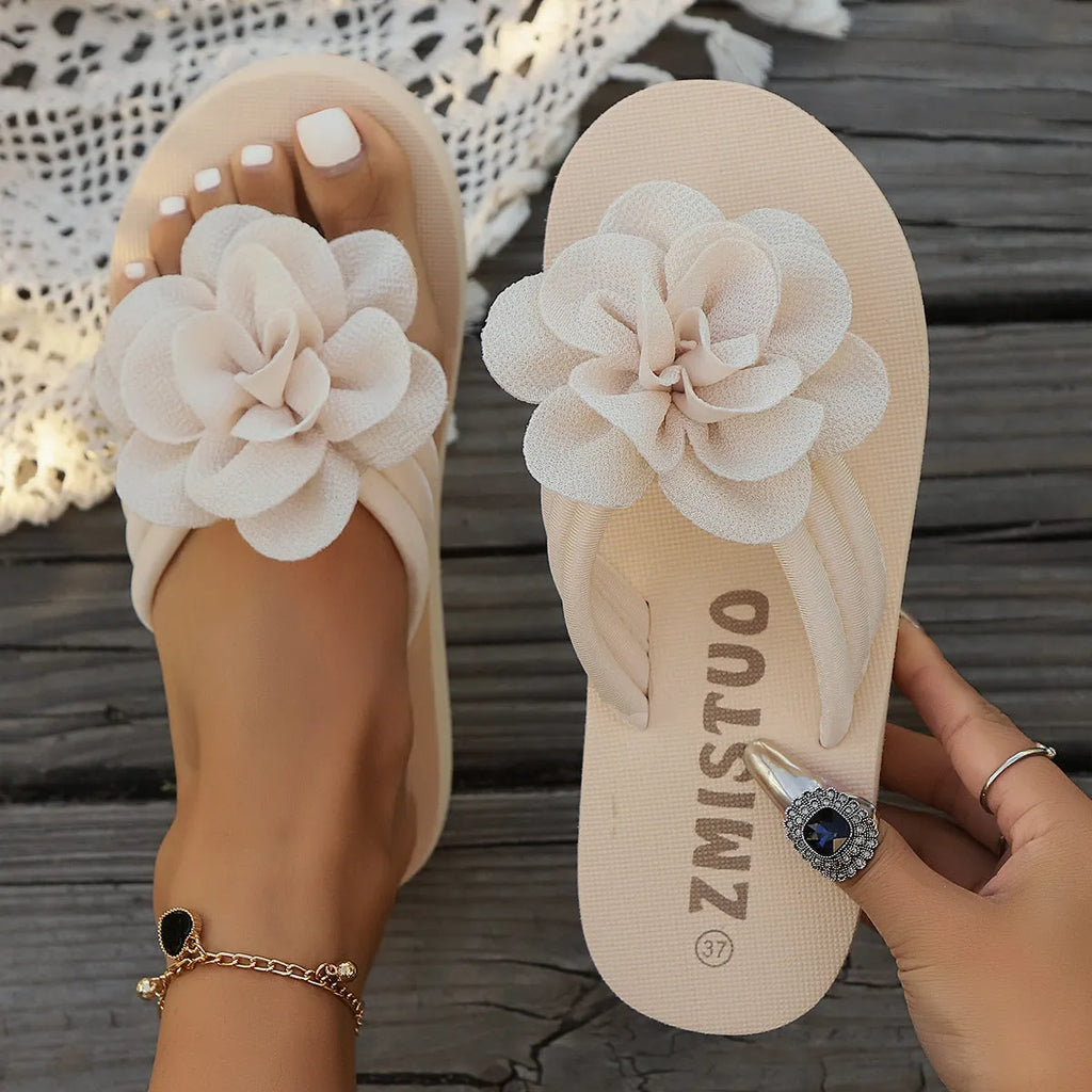 A pair of solid colour flip flop slippers with a small flower detail on the PU upper.