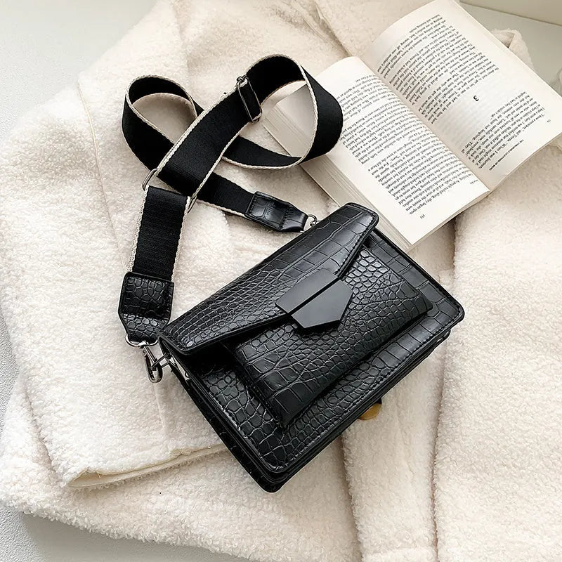 Vintage style black crossbody bag with an adjustable shoulder strap on a mannequin.