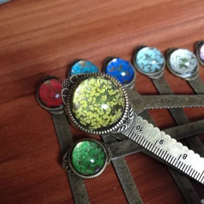 Handmade dried gypsophila and clover flower bookmark ruler on a book, showing 12cm length.