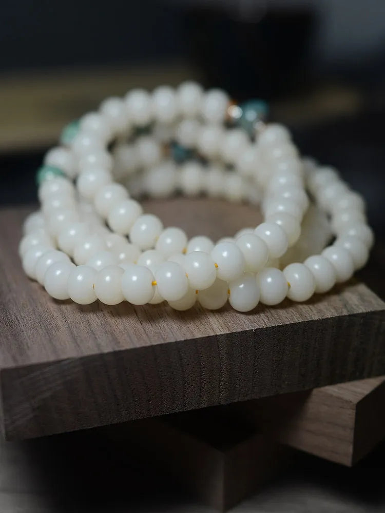 White jade bodhi root oblate bead bracelet with 108 flat round beads in 7x9mm and 8x10mm sizes.