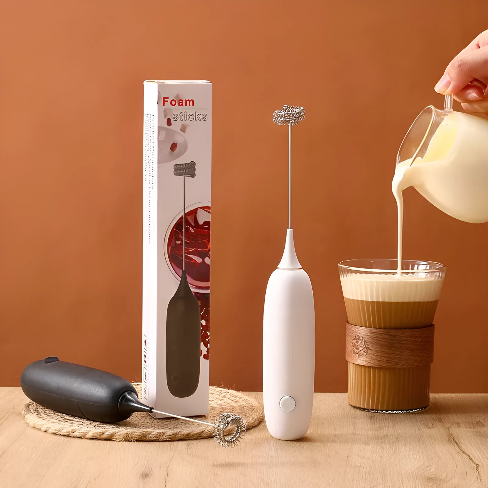 A handheld electric milk frother in black and white colours on a kitchen counter.