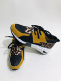 Women's black suede casual sneakers with a low wedge heel on a wooden floor.
