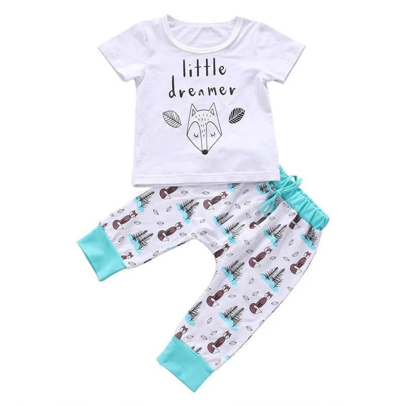 Newborn baby clothes set with white cotton T-shirt and grey pants on a soft background