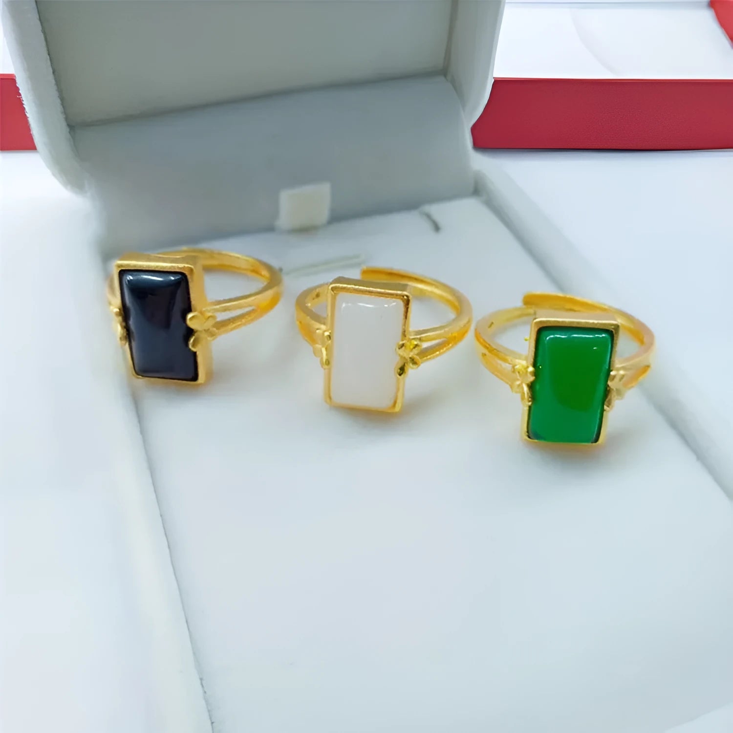 Adjustable brass gold-plated ring with a green artificial gemstone inlay on a finger.