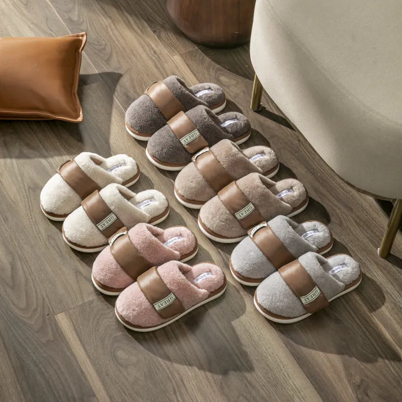 Beige plush velcro slippers with a round toe and non-slip plastic sole on a wooden floor.