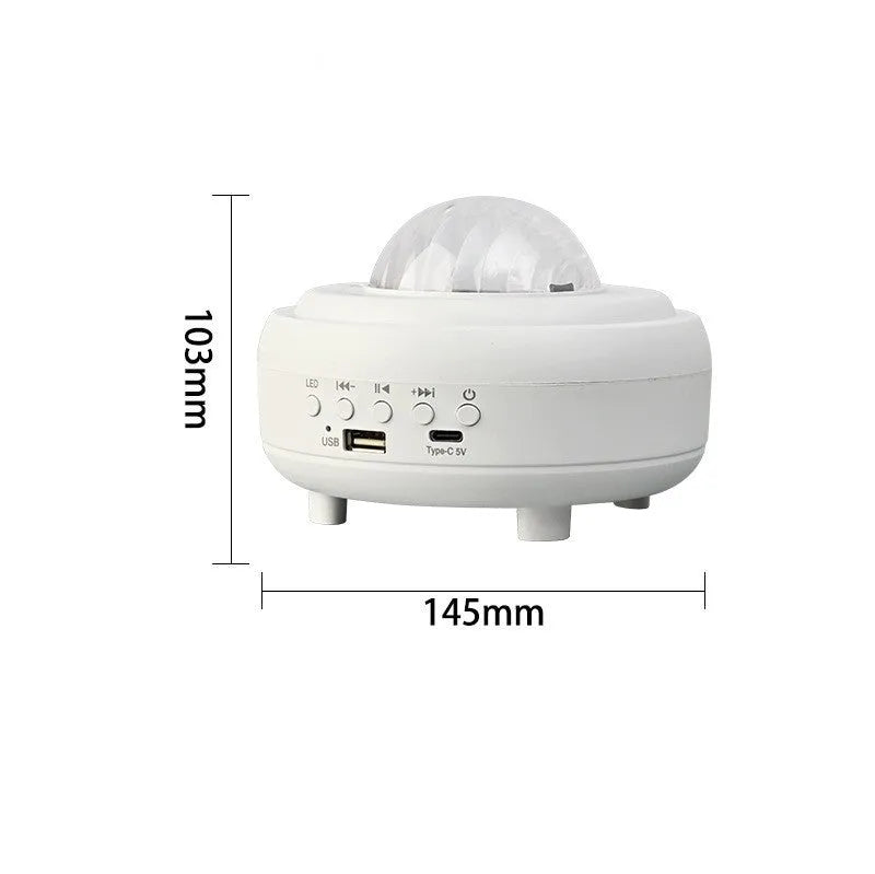 White and black galaxy star projector night light with Bluetooth speaker on a surface.