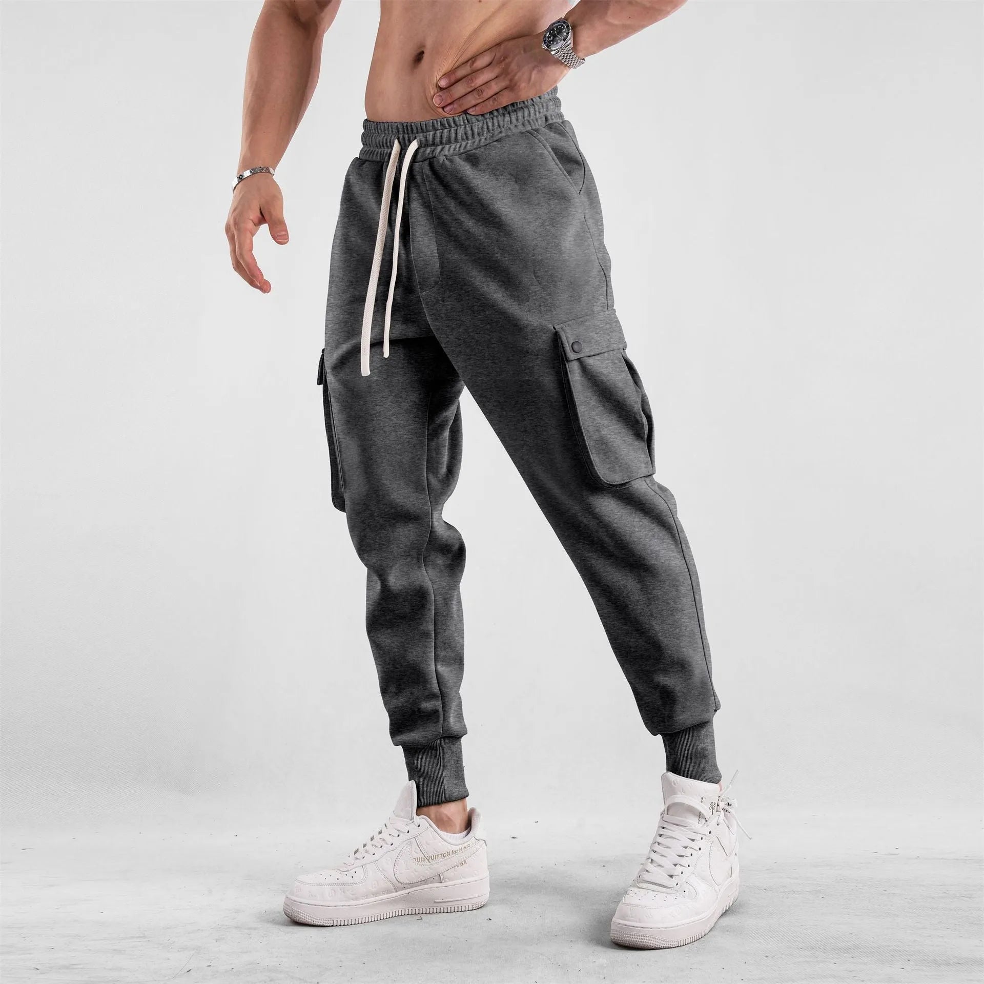 Men's beige ankle-tie loose-fit casual cotton trousers with side pockets on a neutral background.