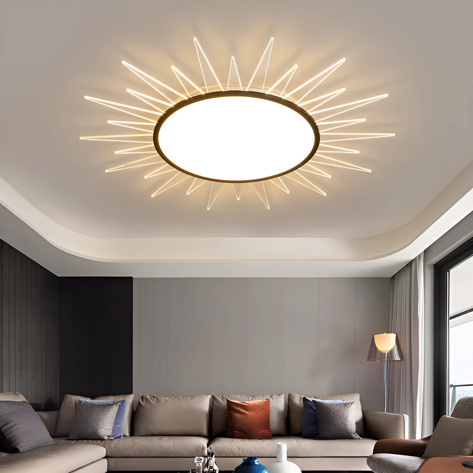 Modern round aluminium ceiling lamp with remote control for dimming, shown in a living room setting.