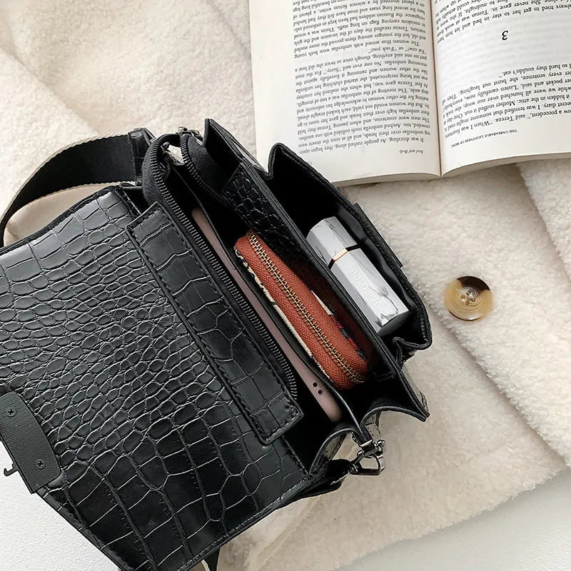Vintage style black crossbody bag with an adjustable shoulder strap on a mannequin.