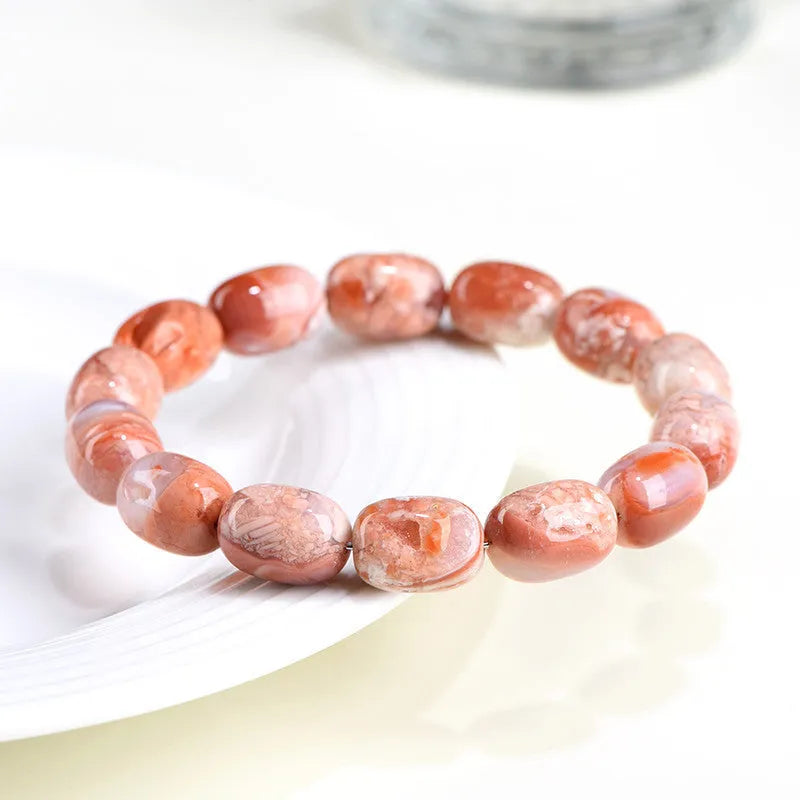 Natural cherry agate bracelet with barrel-shaped beads and a Ruyi design element on a wrist.