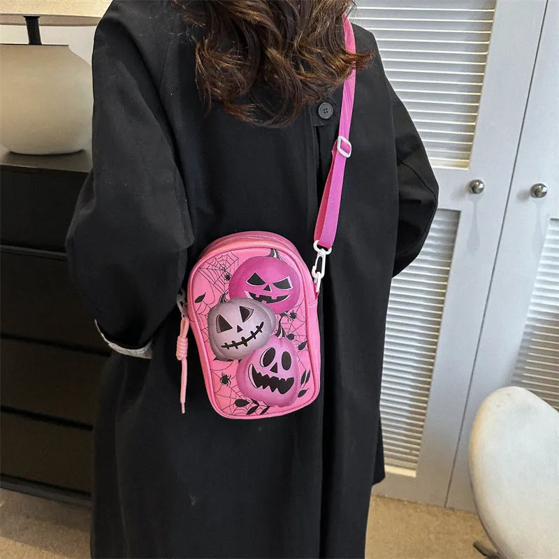 Black Halloween crossbody bag with orange pumpkin, white ghost, and black bat print, showing front zip and adjustable strap.