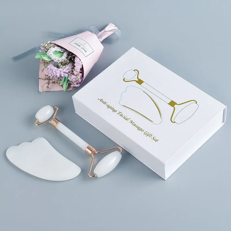 Natural white jade facial roller and gua sha scraper board set on a plain background.