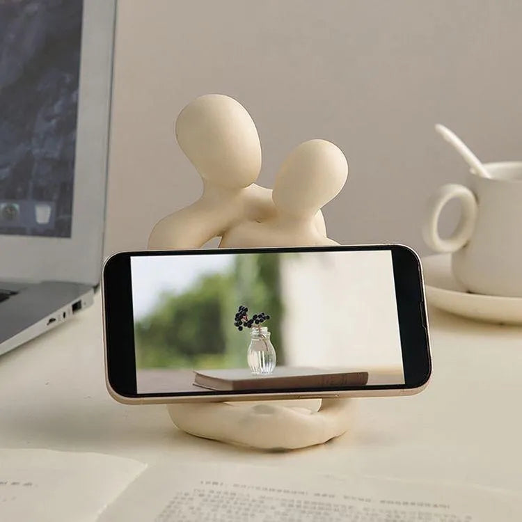 Modern loving couple resin statue in milky white or gold colour on a desk.