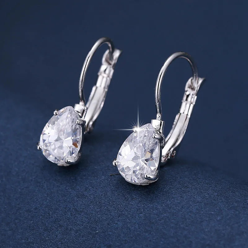 A pair of simple drop-shaped copper earrings with a platinum gem setting, shown in gold colour.