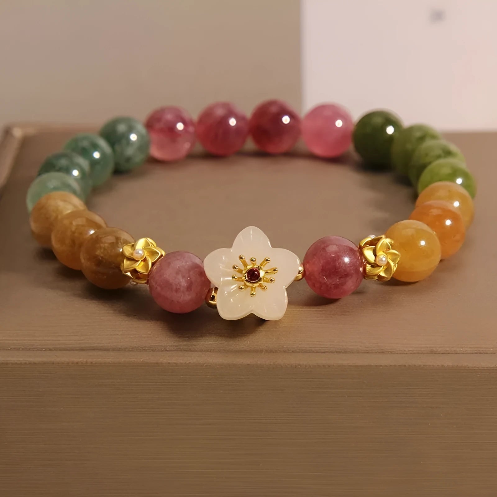 Natural colour tourmaline bracelet with silver electroplated flower and fu character charms on a geometric beaded band.