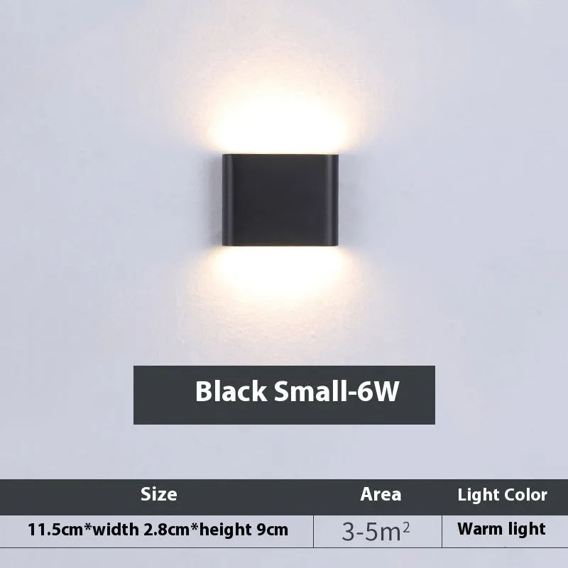 Rectangular LED outdoor wall lamp in black finish with warm light on a brick courtyard wall