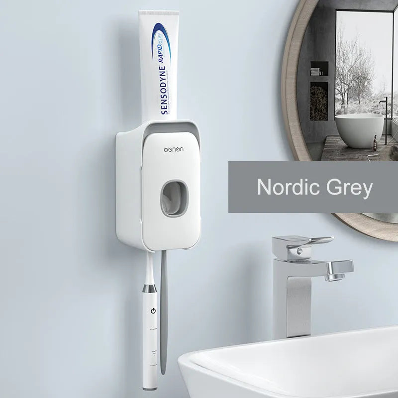 Automatic toothpaste dispenser in grey, blue, and pink colours on a bathroom countertop.