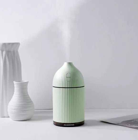 White USB aromatherapy diffuser and humidifier with LED light on a wooden desk