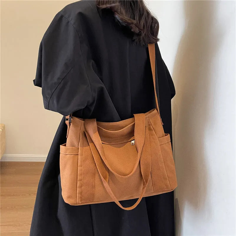 Large solid colour polyester canvas shoulder bag for women showing external pocket and strap.