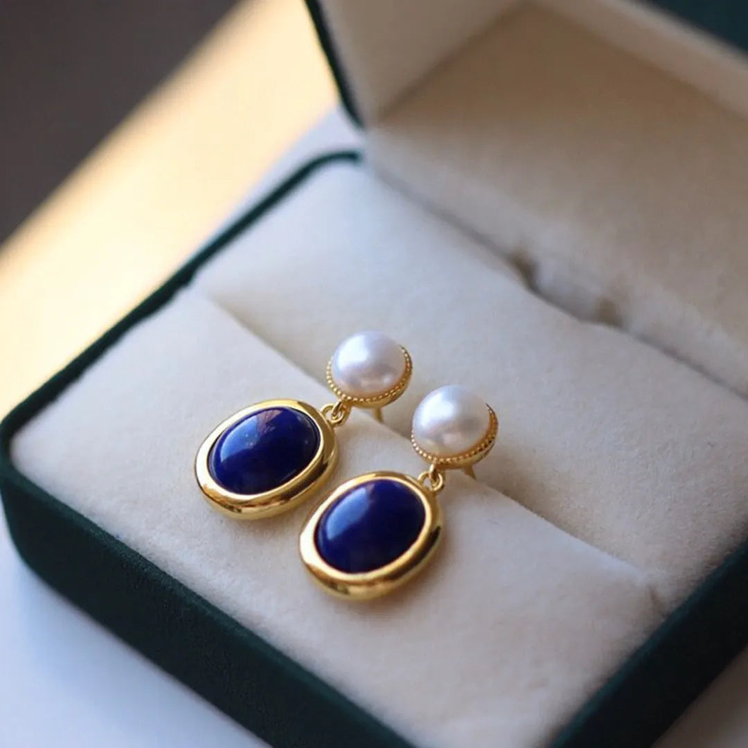 A pair of simple 925 silver earrings featuring a blue lapis lazuli pearl and auspicious pattern detailing.