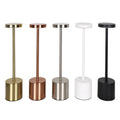Modern minimalist iron table lamp with silver finish, I-shaped silhouette, emitting warm ambient light on a bedside table