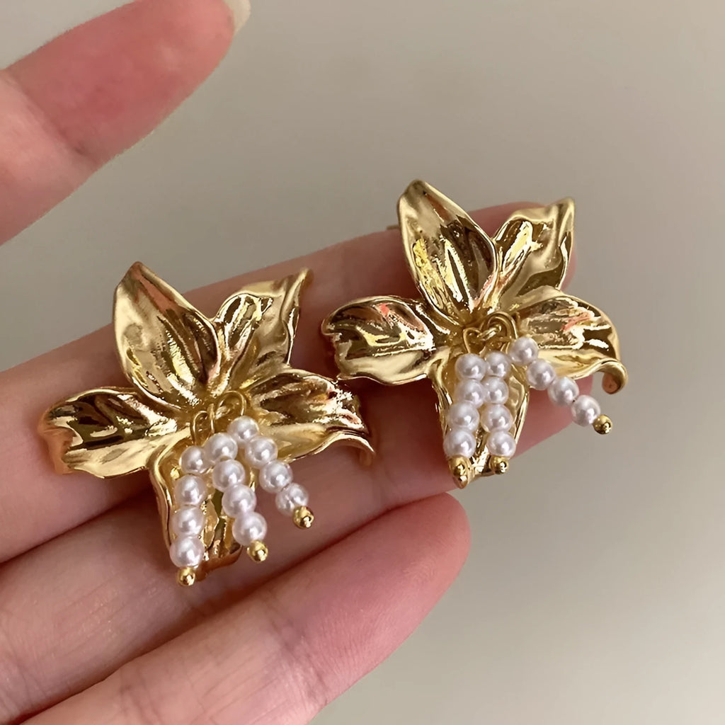 Gold H1795 metal flower earrings with an exaggerated floral design and pearl details.