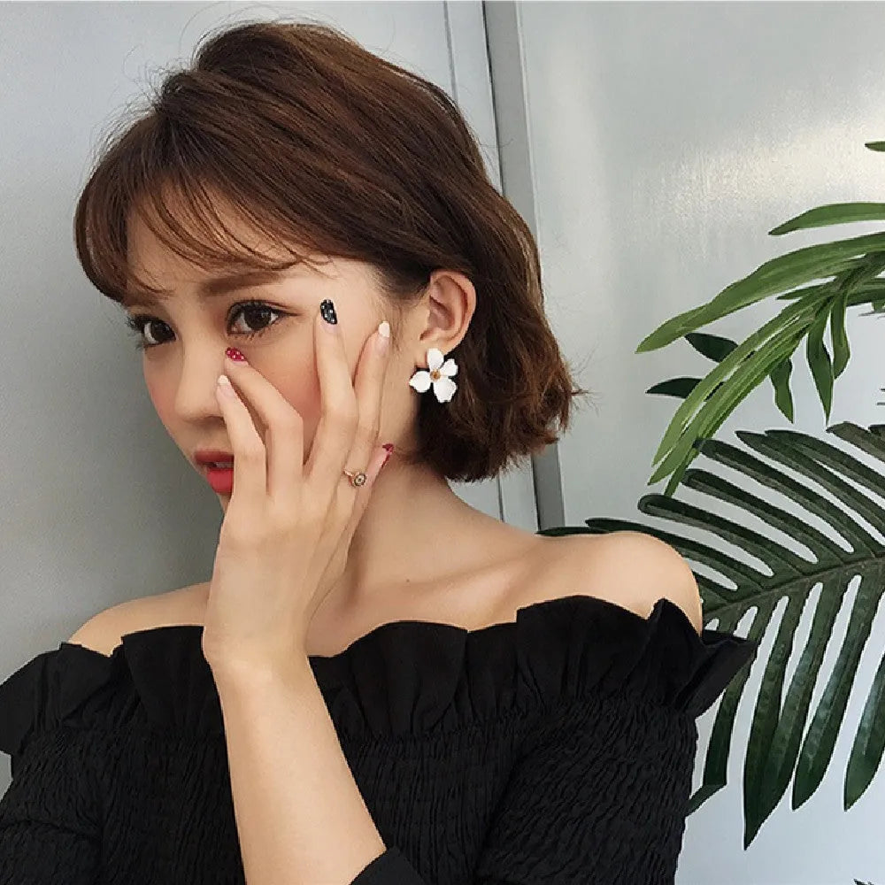 A pair of small floral-shaped stud earrings in alloy, shown in pink and white colour options.
