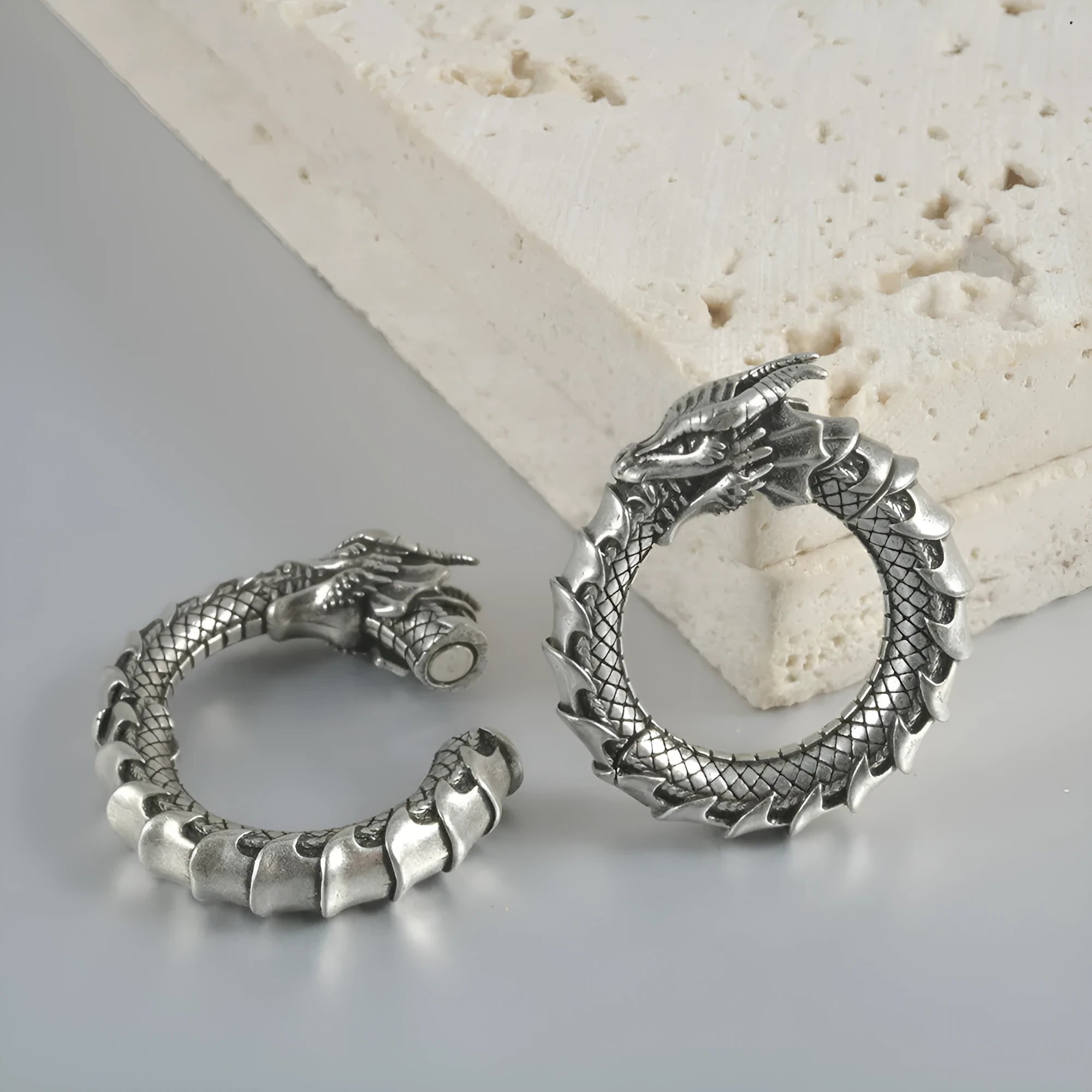 Pair of antique silver dragon-shaped geometric earrings with hollow-out design on a plain background.