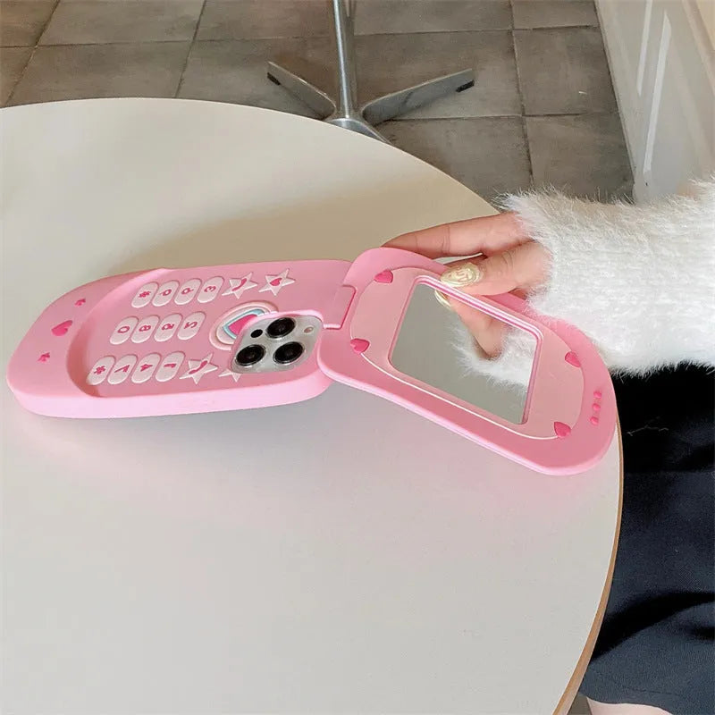 Pink silicone iPhone case shaped like a flip phone with a built-in mirror on the front.