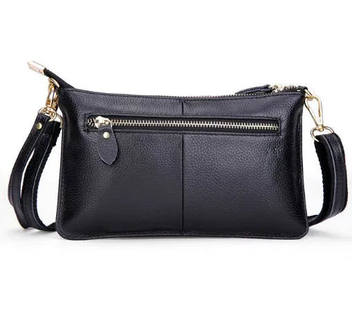 A small lady's cowhide slant handbag in claret colour, showing the hand strap and long shoulder strap.