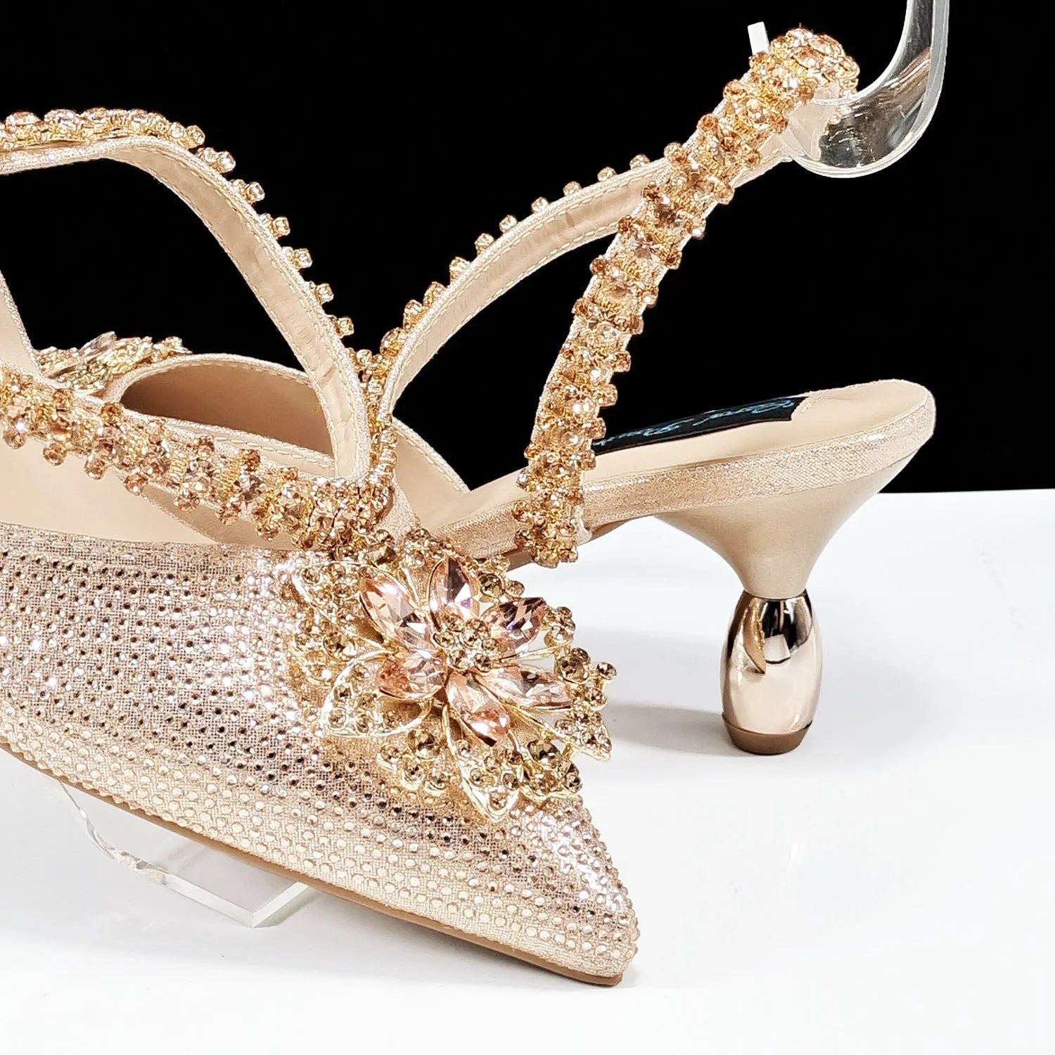 Women's black high heel shoe with floral rhinestone detail and matching hard clutch bag.